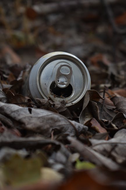 A large green waste disposal bin filled with various discarded materials, including numerous cardboard boxes of different sizes and shapes, some flattened and others partially assembled, as well as a 